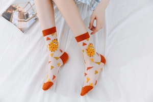 Detail of sheer mesh socks with cartoon pufferfish patterns and vibrant orange accents