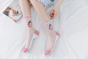 Detail showing sheer mesh socks with peach embroidery and striped cuffs in soft light