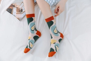 Close-up of artistic avocado pattern on mesh cotton socks with orange contrast trim