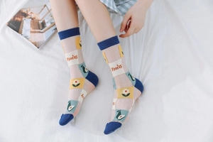 Close-up of sheer mesh crew socks featuring avocado patterns and flowers text on feet