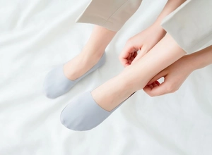 Close-up of seamless light blue ice silk no-show socks on model feet with white background