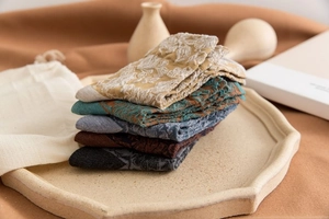 Detail view of five pairs of vintage floral patterned knit socks on a ceramic tray