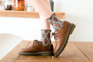 Close-up of grey jacquard mid-calf cotton socks with bohemian pattern and leather shoes