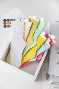 Close-up of colorful ribbed slouch socks in multiple candy colors on a white tray