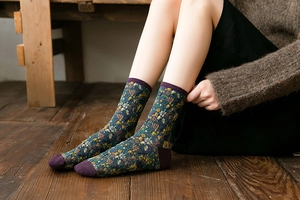 Detail of cable knit crew socks with vintage floral jacquard and purple ribbed cuffs