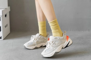 Close-up of retro chunky sneakers with orange TPU heel detail and yellow slouch socks