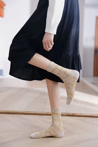 Detailed knit texture of mustard yellow crew socks with retro white floral patterns