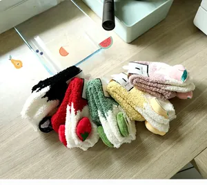 Detail von fünf Paar dicken Korallenfleece-Wintersocken mit 3D-Fruchtdekor auf Holz