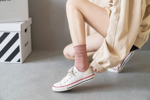 Detail of dusty pink ribbed slouch socks paired with casual white canvas sneakers