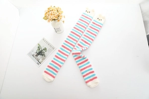 Détail de chaussettes hautes en polaire corail à rayures roses et bleues et visage mignon