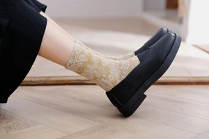 Detailed view of ginger yellow socks with white floral jacquard and black loafers