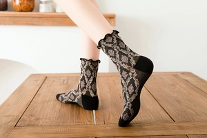 Detailed view of vintage baroque pattern knit socks with ruffled cuffs on a wood surface