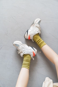 Macro shot of stylish velvet slouch socks paired with chunky sneakers on gray pavement