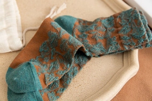 Close-up of vintage knit socks featuring 3D floral relief pattern in brown and teal