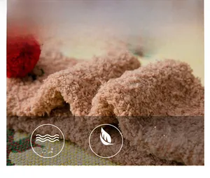 Close-up of thick light brown coral fleece fabric with soft texture and red pompom detail