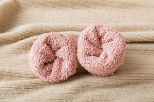 Close-up of soft pink coral fleece socks on a cozy beige knitted blanket background