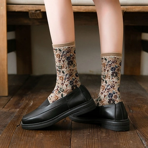 Vintage floral knit socks paired with black loafers on a rustic wooden floor