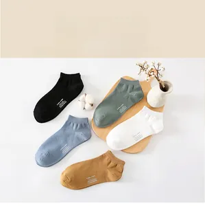 Flat lay of men's low-cut cotton socks in five colors on a natural wooden tray