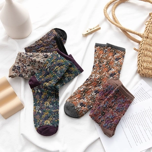 Cozy vintage floral cable knit crew socks in assorted colors on a soft fabric backdrop