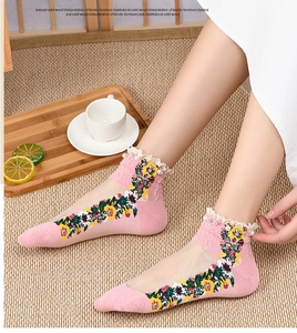 Detail of pink vintage socks featuring floral embroidery, lace trim, and pearl accents