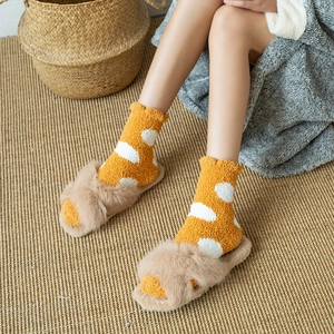 Thick coral fleece yellow polka dot socks and plush slippers on a woven mat