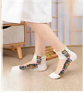 Detail of white cotton socks with floral embroidery, lace trim, and pearl accents