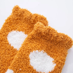 Macro shot of thick ginger coral fleece socks with white heart and polka dot patterns