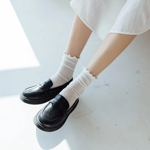 Close-up of white mesh lace ruffle socks paired with black platform loafers shoes