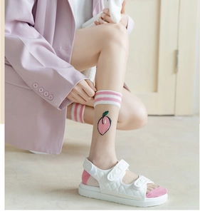 Detail von durchsichtigen Netzsocken mit Pfirsich-Stickerei und weißen Klettsandalen