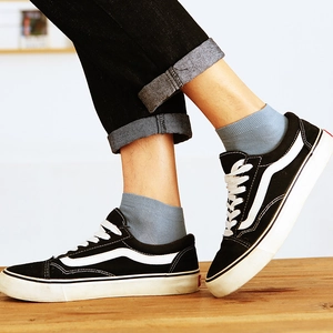 Light grey cotton low cut socks for men worn with black canvas shoes and denim jeans