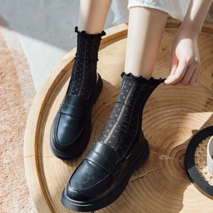 Detail of black polka dot mesh socks with ruffled trim and vintage leather loafers