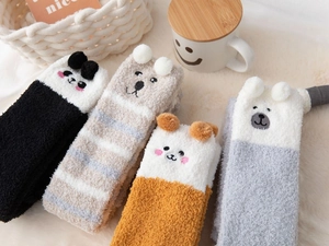 Detail of four fluffy coral fleece animal socks with ears on a warm home background