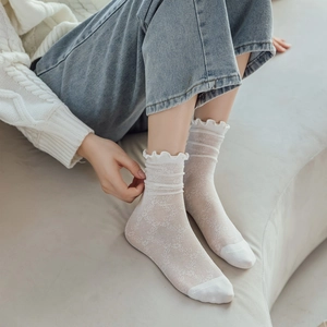 Close-up of white mesh socks with ruffled lace cuffs and delicate hollow knit patterns