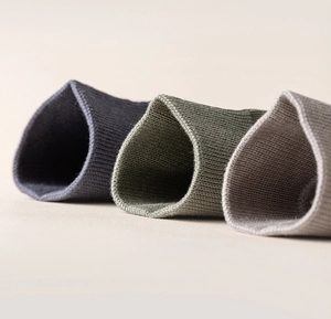 Detail of ribbed knit cuffs on combed cotton mid-calf socks in navy, olive and grey