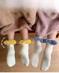 Detailed close-up of fluffy coral fleece socks with decorative plush bows on wooden floor