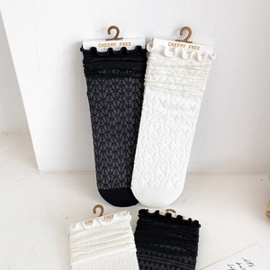 Close-up of black and white cotton mesh socks with elegant ruffle edge detail