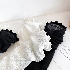 Close-up of delicate floral lace textures and wavy edges on black and white cotton socks