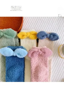 Five pairs of coral fleece socks in pastel colors with large bow detail on white fabric
