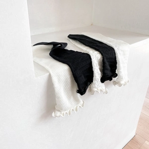 Detailed knit texture of black and white ruffle edge cotton socks with hollow patterns