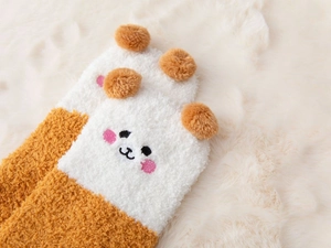 Detailed close-up of warm coral fleece socks with cute cartoon embroidery and 3D plush balls