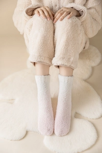 Nahaufnahme weicher korallenvlies Socken in Rosa mit Farbverlauf auf weißem Bär Teppich