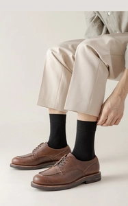 Detail of brown leather moccasins paired with black ribbed cotton mid-calf socks