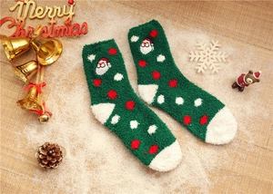Festive green coral fleece Christmas socks with Santa Claus embroidery on wooden background