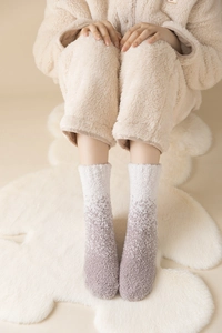 Detailaufnahme von kuscheligen Korallenvlies Socken mit Farbverlauf auf weichem Teppich