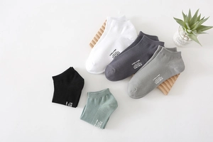 Detail of multi-color low-cut cotton socks with printed brand logo on natural wood display
