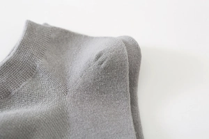 Macro shot of grey cotton knit boat sock showing precise ribbed stitching and heel detail