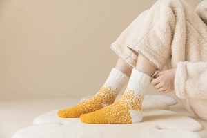 Detail von weichen gelb-weißen Korallenvlies-Socken auf flauschigem Teppich für Winterkomfort