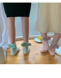Close-up of thick coral fleece warm socks with 3D bowknot detail in green and pink