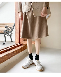 Detail view of khaki knit midi skirt with black mid-calf socks and retro sneakers