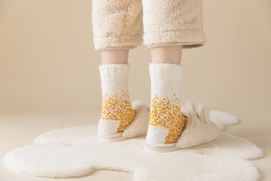 Nahaufnahme von Korallenvlies-Socken mit gelben Punkten auf weichem Blumenteppich